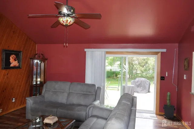 a living room with furniture a ceiling fan and a large window