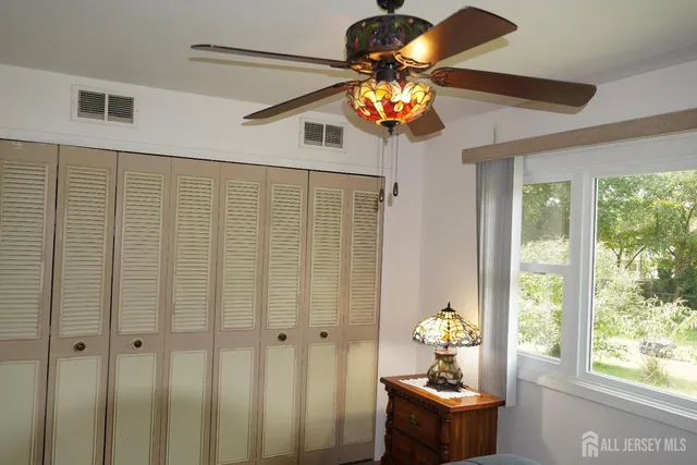 a room with chandelier fan and windows