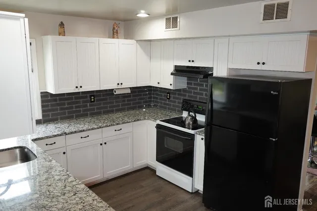 a kitchen with granite countertop white cabinets and stainless steel appliances