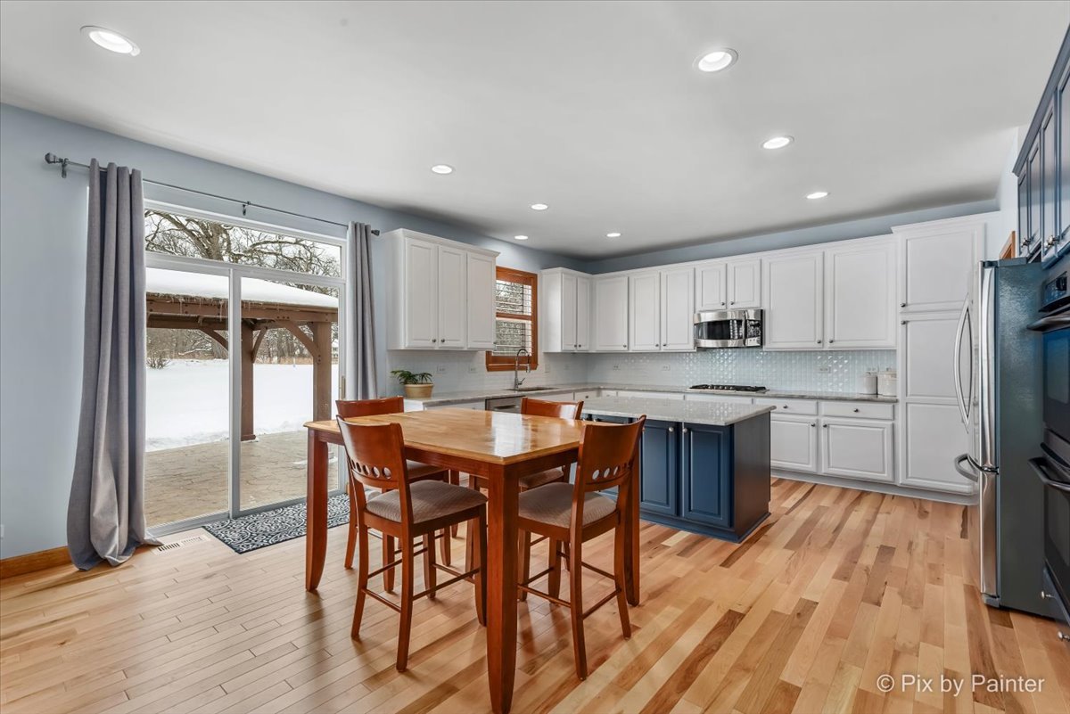 488 Newcastle Drive Cary, IL 60013 - Photo 12 of 33 a kitchen with stainless steel appliances granite countertop a kitchen island hardwood floor sink stove dining table and chairs