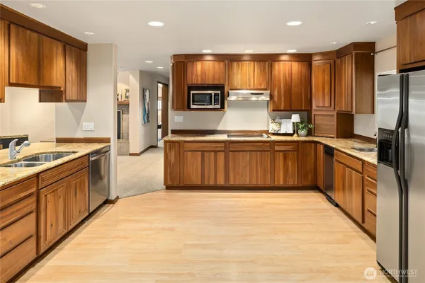 a large kitchen with stainless steel appliances kitchen island granite countertop a stove refrigerator and cabinets