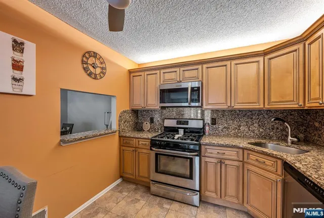 a kitchen with stainless steel appliances granite countertop a stove a sink and a microwave
