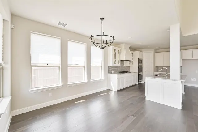 a open kitchen with white cabinets and wooden floor