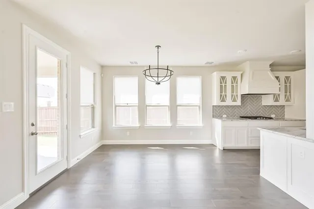 a kitchen with stainless steel appliances granite countertop a stove a sink and white cabinets with wooden floor next to windows