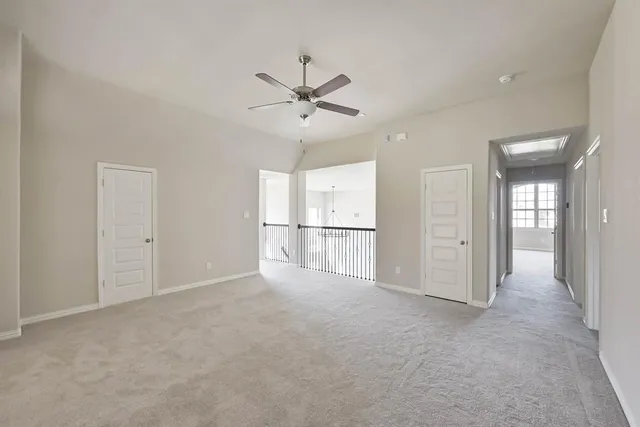 an empty room with chandelier fan and windows