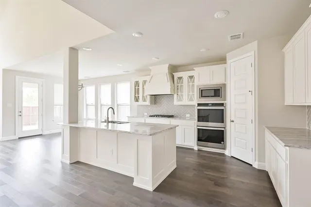a large kitchen with kitchen island wooden floors and stainless steel appliances
