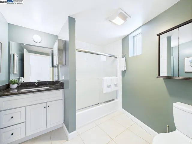 a spacious bathroom with a granite countertop sink a toilet and a mirror