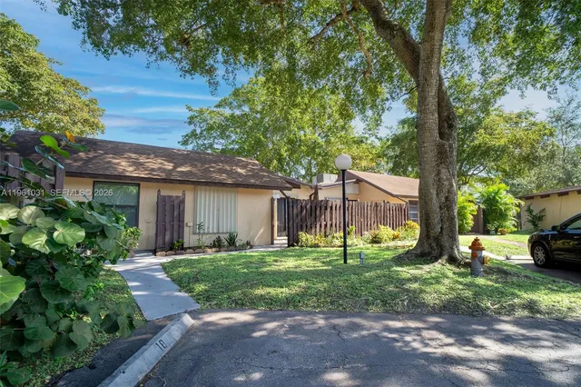 a view of a yard with plants and a table and chair