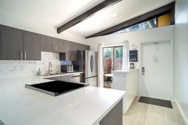 a kitchen with stainless steel appliances a sink a stove a refrigerator a microwave oven and white cabinets with wooden floor