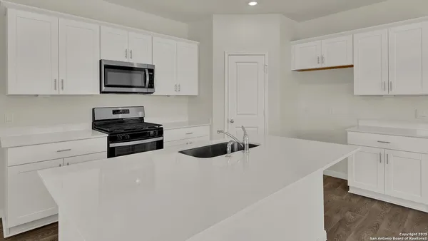 a kitchen with white cabinets and appliances