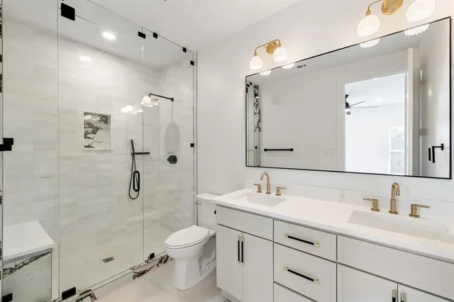 a bathroom with a granite countertop sink a toilet and shower