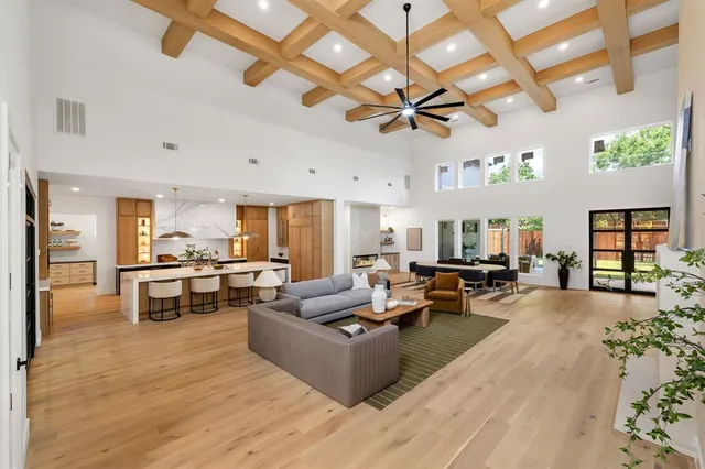 a living room with furniture kitchen view and a wooden floor
