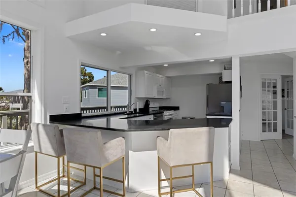 a kitchen with stainless steel appliances kitchen island granite countertop a dining table chairs and a refrigerator