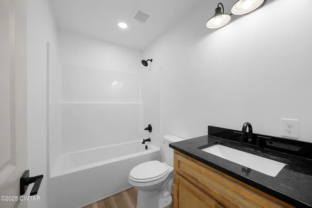 a bathroom with a granite countertop sink a toilet and bathtub
