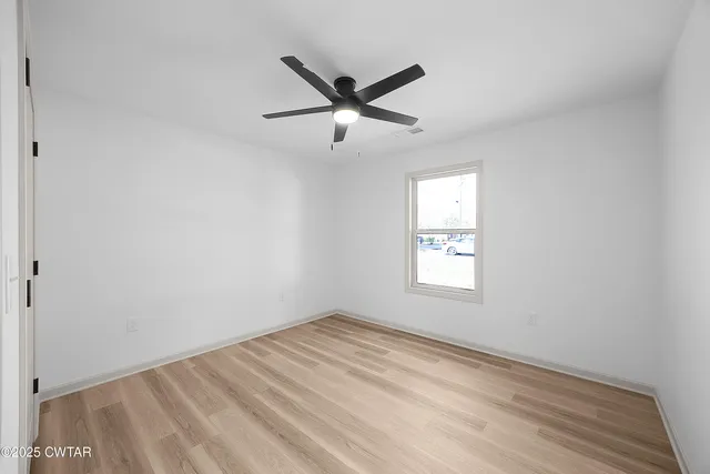 a view of empty room with window and ceiling fan