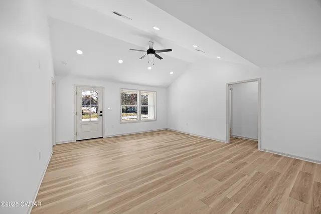 a view of an empty room with a window and wooden floor
