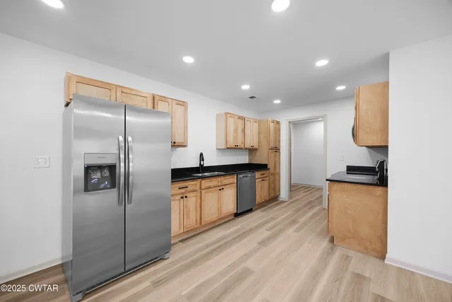 a kitchen with granite countertop a refrigerator and a sink