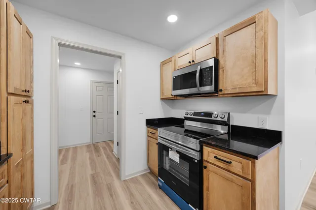 a kitchen with granite countertop wooden cabinets and a stove top oven