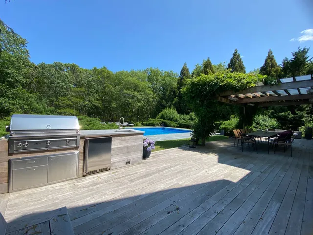 a view of a patio with table and chairs with wooden floor and fence