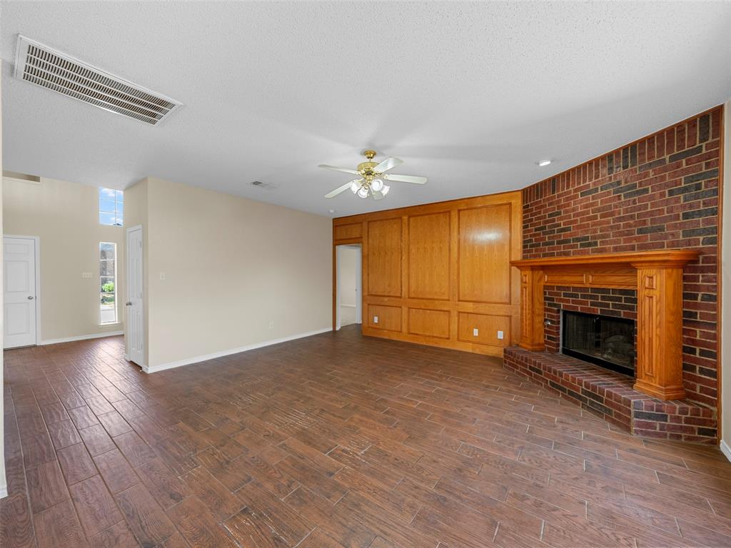 741 Aspen Court Allen, TX 75002 - Photo 21 of 40 Downstairs living room featuring dark wood finished floors, ceiling fan, and a brick fireplace