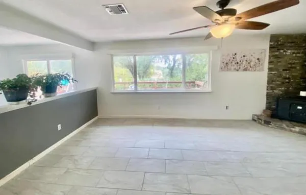 a view of an empty room with a window and kitchen view