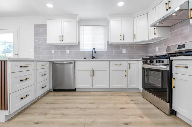 a kitchen with granite countertop white cabinets and stainless steel appliances