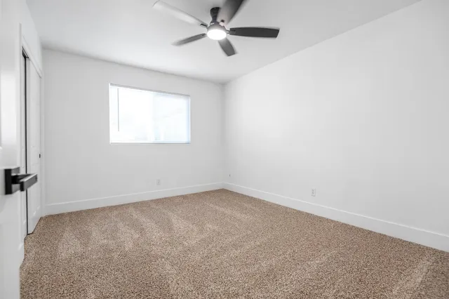 an empty room with a window and a fan