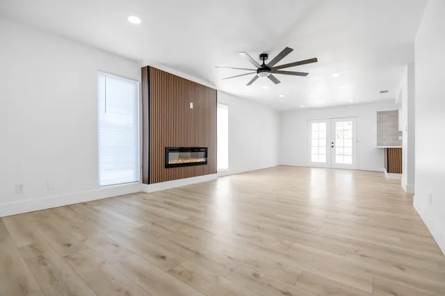 a view of an empty room with window and wooden floor