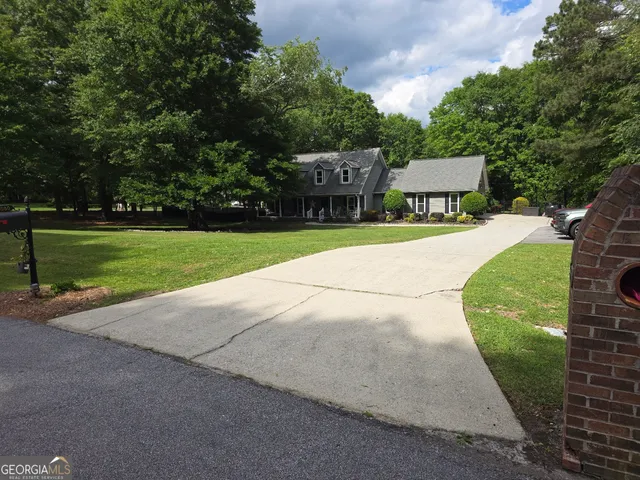 a pathway of a house with a yard and large trees
