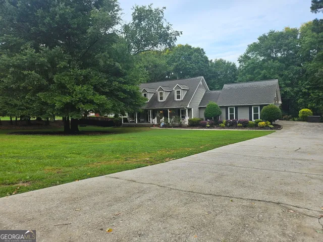 a backyard of a house with plants and large tree