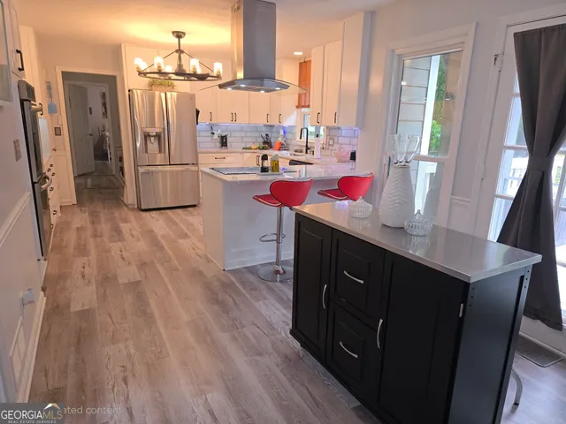 a kitchen with stainless steel appliances kitchen island granite countertop a refrigerator and cabinets