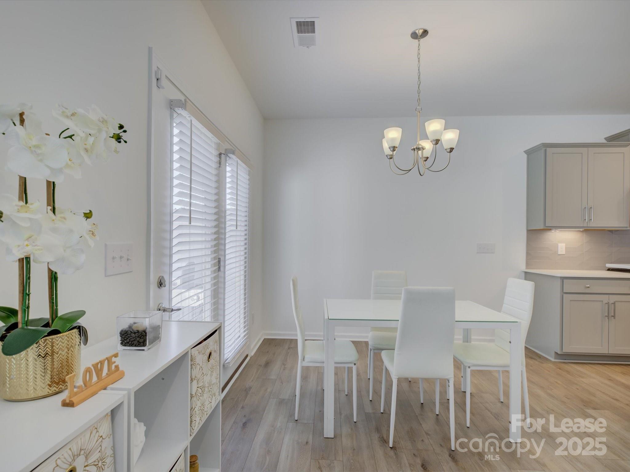 13124 Rover Street Charlotte, NC 28273 - Photo 19 of 46 a view of a dining room with furniture a chandelier and wooden floor