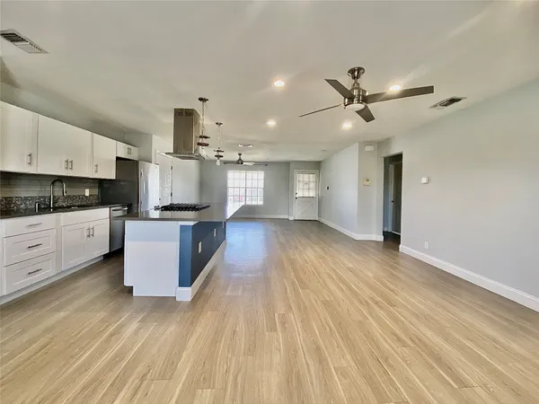 a kitchen with stainless steel appliances kitchen island wooden floors and view living room
