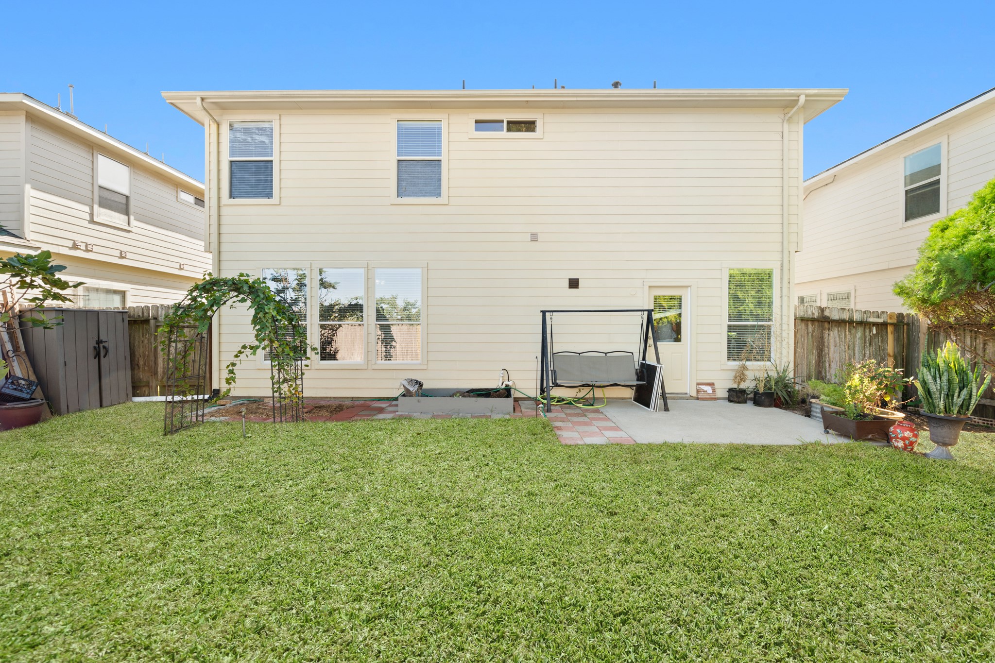 3214 Vinca Ranch Drive Katy, TX 77494 - Photo 21 of 26 Expansive backyard with a wide patio and open green space, ideal for outdoor dining, grilling, or recreation. The exterior of the home is well-kept with light siding and large windows.