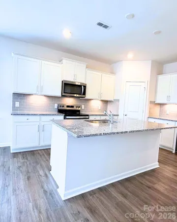 a kitchen with granite countertop a sink cabinets and wooden floor