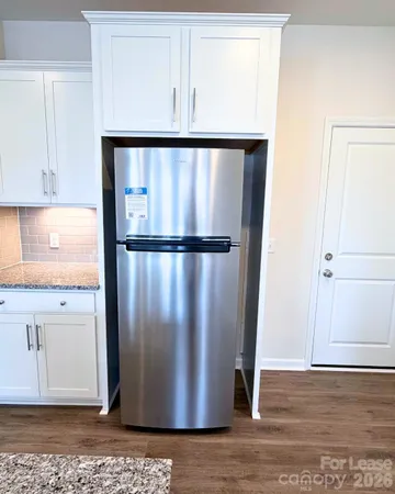 a view of a refrigerator in kitchen and an empty room