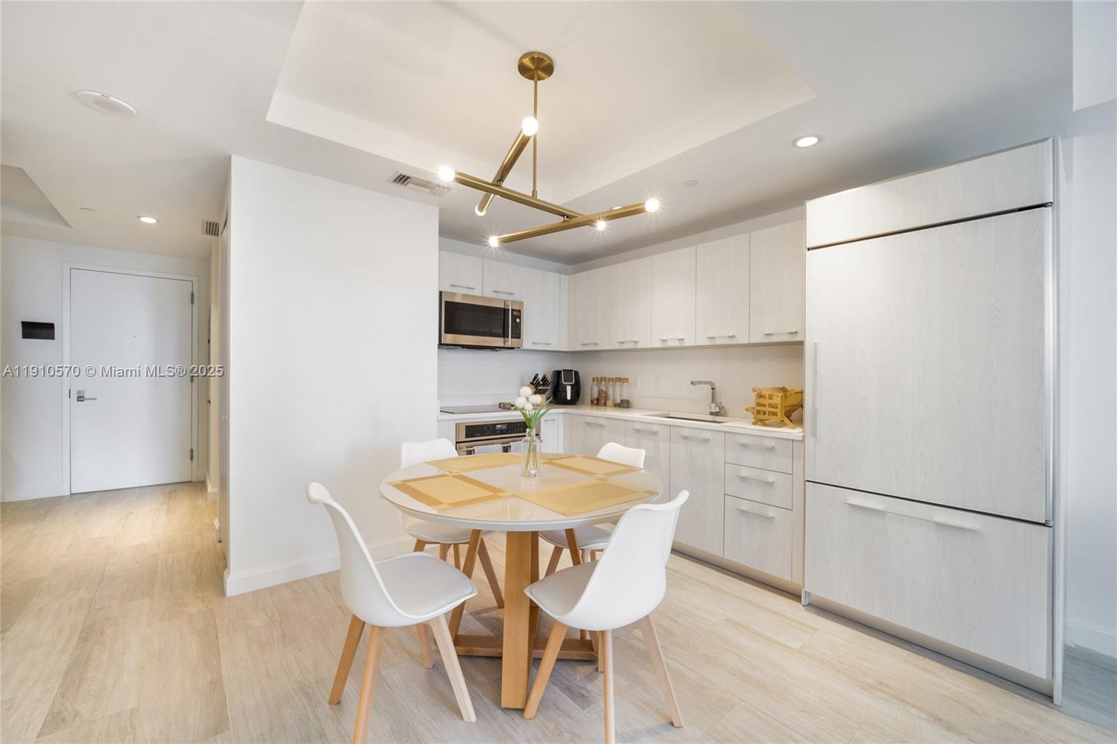 45 Southwest 9th Street, Unit 1904 Miami, FL 33130 - Photo 3 of 15 a kitchen with stainless steel appliances a refrigerator a stove a dining table and chairs with wooden floor