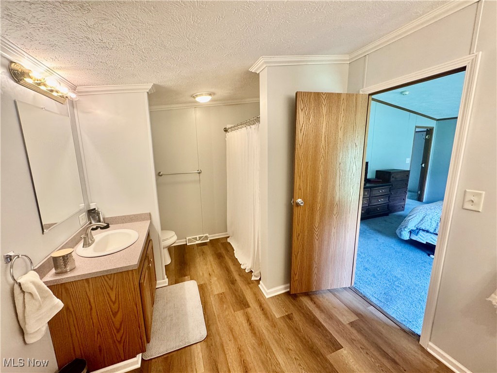 3264 Simpson Road Southeast Dennison, OH 44621 - Photo 15 of 29 Full bath featuring a textured ceiling, vanity, crown molding, wood finished floors, and ensuite bathroom