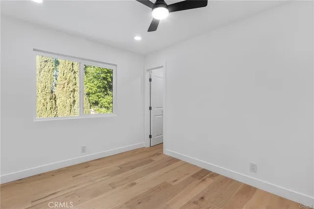 an empty room with wooden floor chandelier fan and windows