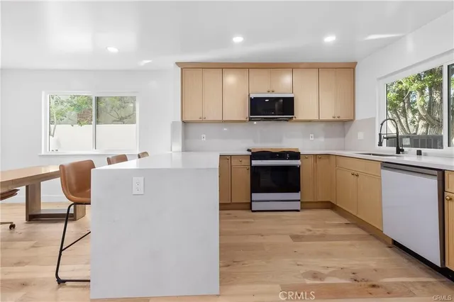 a kitchen with kitchen island granite countertop a stove top oven a sink dishwasher a dining table and chairs with wooden floor