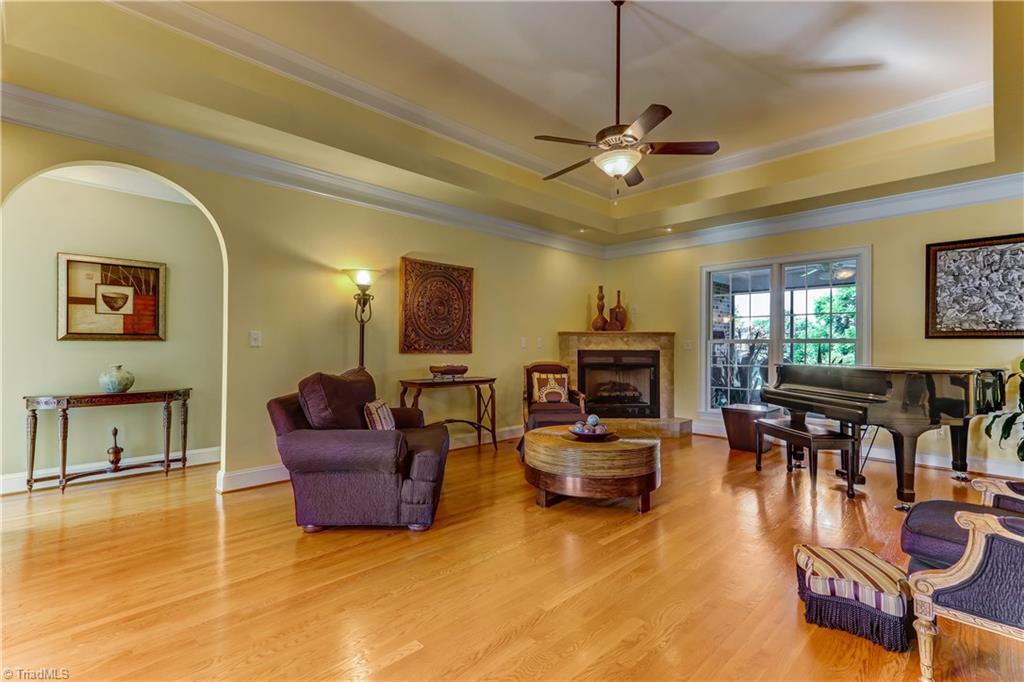 5403 Red Fox Drive Oak Ridge, NC 27310 - Photo 2 of 30 The Great Room has hardwood floors, Crown molding, Cove ceiling with lighting accents, ceiling fan with light. Accent lighting over gas fireplace. Not shown in this view, built-in cabinets with open and closed storage.