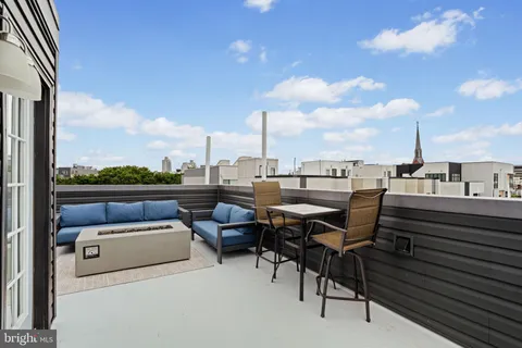 a roof deck with couches and a potted plant on it