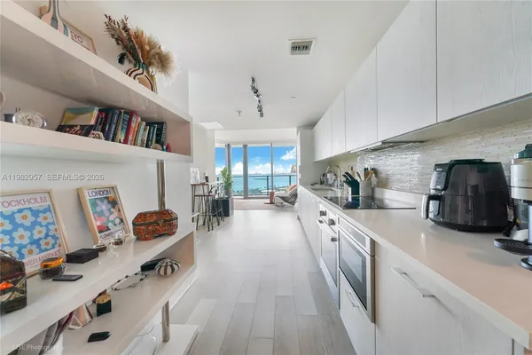 a large white kitchen with stainless steel appliances lots of counter space and window