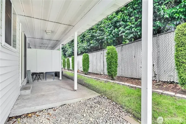 a backyard of a house with table and chairs and wooden fence