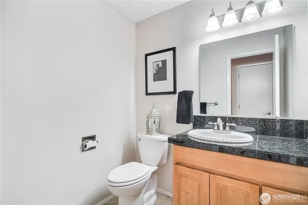 a bathroom with a granite countertop sink mirror vanity and toilet