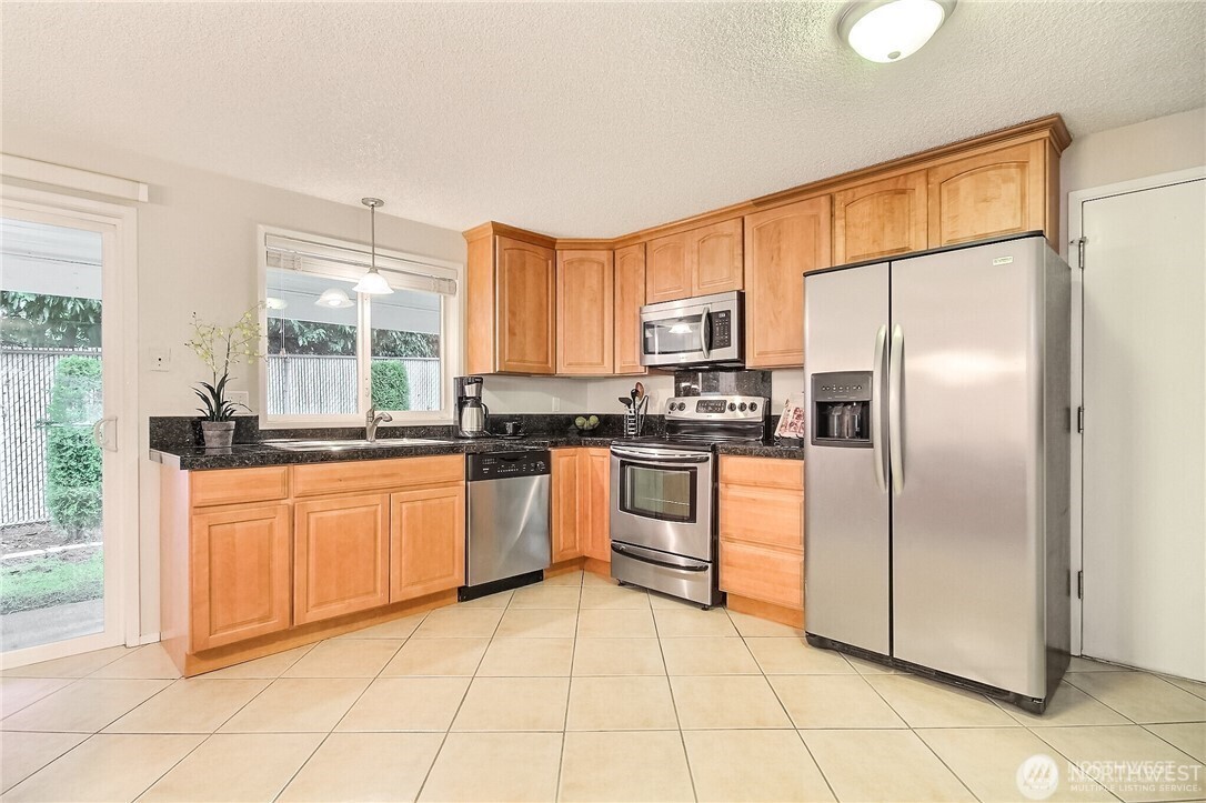4514 Southwest 319th Place, Unit D Federal Way, WA 98023 - Photo 9 of 21 a kitchen with stainless steel appliances granite countertop a refrigerator sink and cabinets
