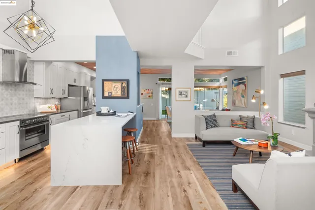 a kitchen with stainless steel appliances granite countertop a refrigerator a stove a sink dishwasher a dining table and chairs with wooden floor