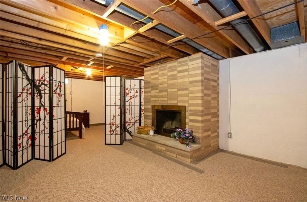 2530 Tuckahoe Road Wooster, OH 44691 - Photo 26 of 29 Finished basement space featuring a brick-surround fireplace with hearth, exposed wood ceiling joists, and neutral carpeting