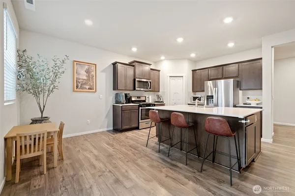 a kitchen with kitchen island granite countertop wooden floors and a refrigerator