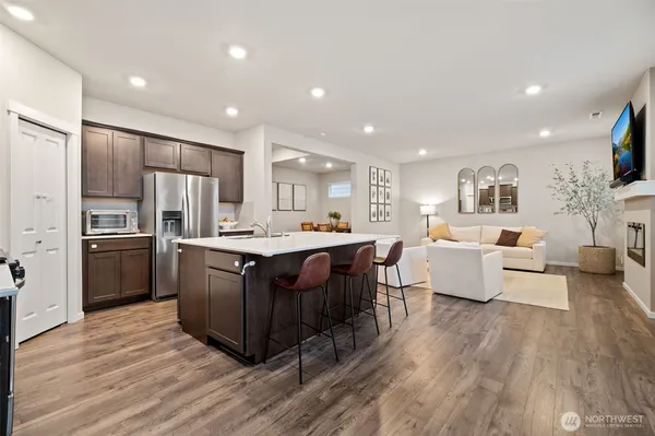 a living room with stainless steel appliances kitchen island granite countertop a large center island and a wooden floor